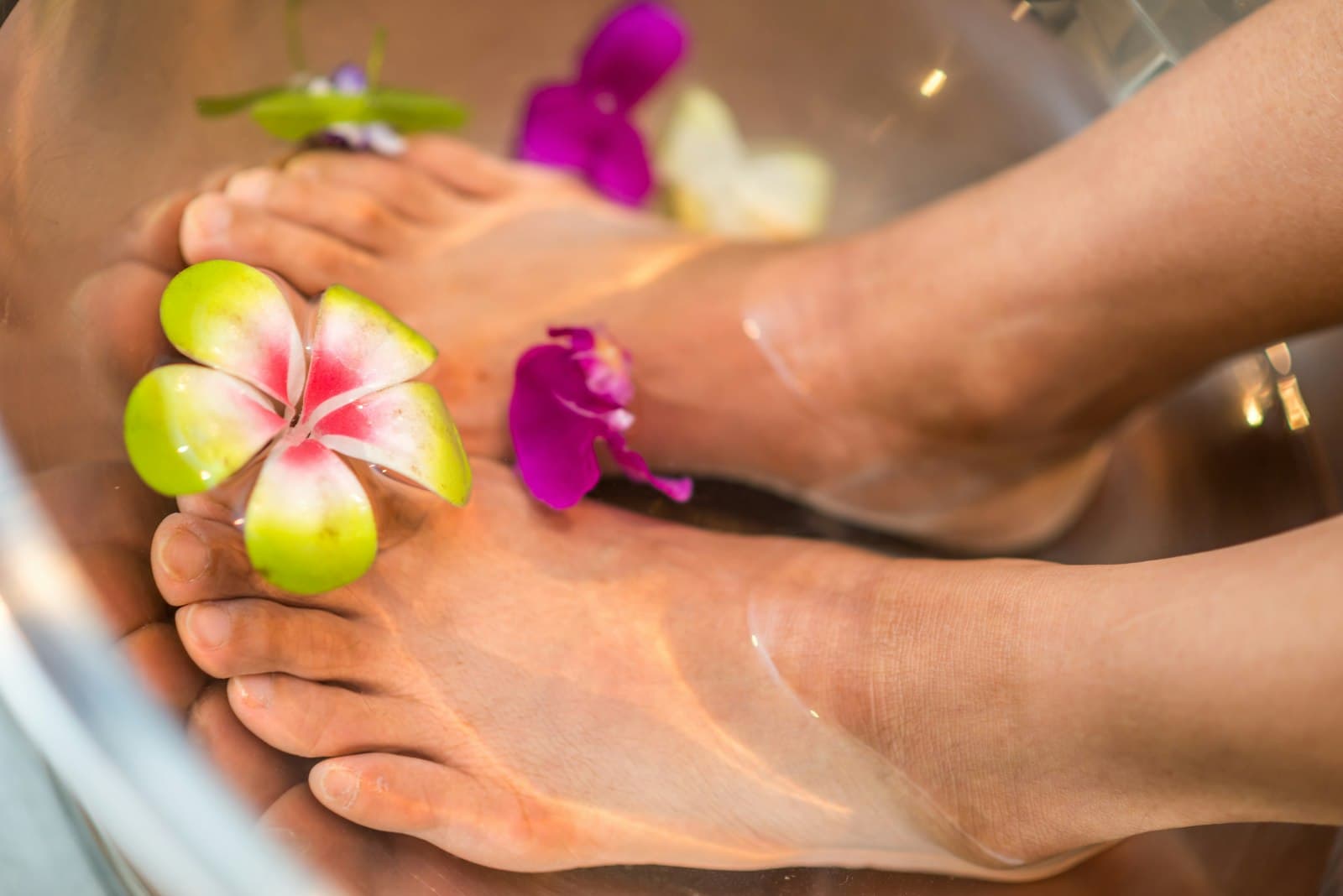 A client's feet in a flower-filled footbath at a pedicure station